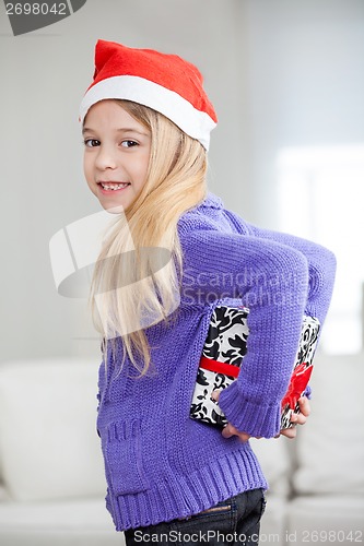 Image of Smiling Girl Hiding Christmas Present Behind Back