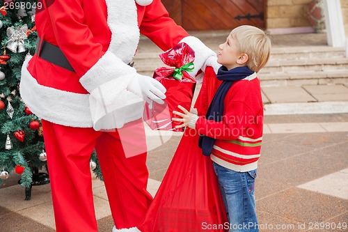 Image of Santa Claus Giving Gift To Boy