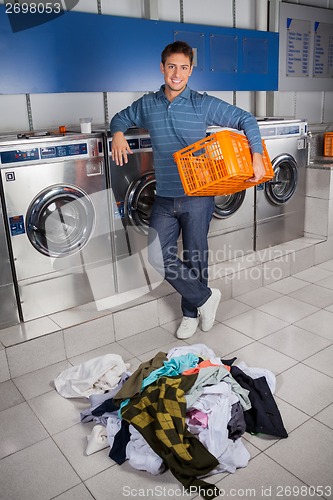 Image of Happy Man Holding Empty Basket With Dirty Clothes On Floor