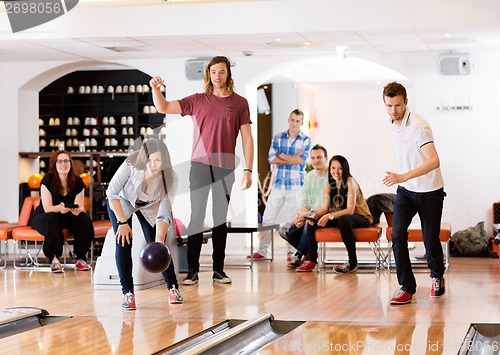 Image of Man And Woman Bowling With Friends in Background