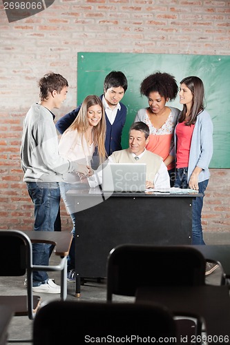 Image of Students And Teacher Discussing Over Laptop In Classroom