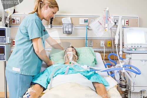 Image of Nurse Adjusting Male Patient's Pillow