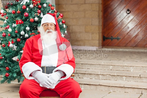 Image of Santa Claus Sitting Against Christmas Tree