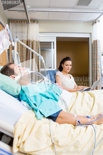 Image of Woman With Laptop Sitting By Patient In Hospital