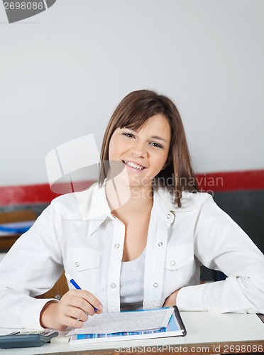 Image of Happy Teenage Schoolgirl Sitting At Desk