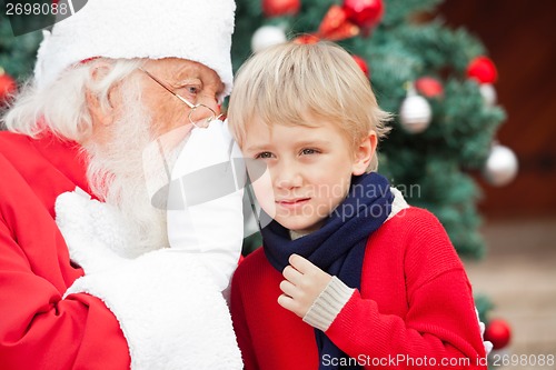 Image of Santa Claus Whispering In Boy's Ear