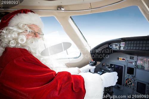 Image of Santa Holding Control Wheel In Cockpit Of Private Jet