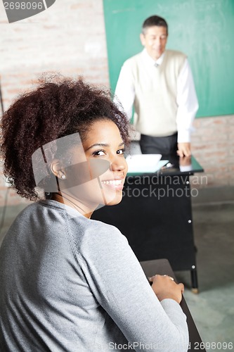 Image of Student With Professor Standing In Background At Classroom