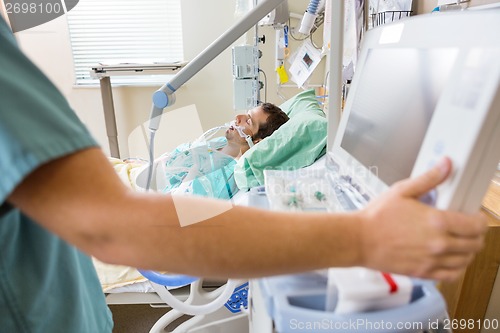 Image of Nurse Pressing Monitor's Button With Patient Lying On Bed