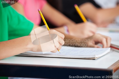 Image of Classmates Writing In Book At Desk