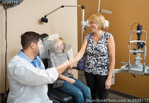 Image of Optician And Woman Shaking Hands While Looking At Boy