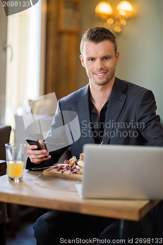 Image of Business man With Mobilephone And Laptop In Restaurant