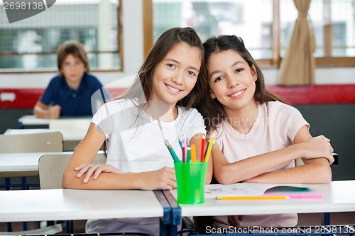 Image of Cute Schoolgirls Sitting Together At Desk