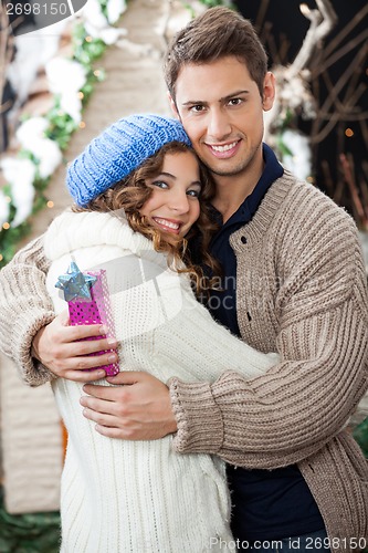 Image of Couple With Gift Box Embracing At Christmas Store