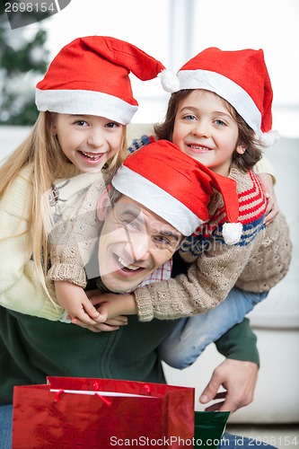 Image of Playful Father Piggybacking Children During Christmas