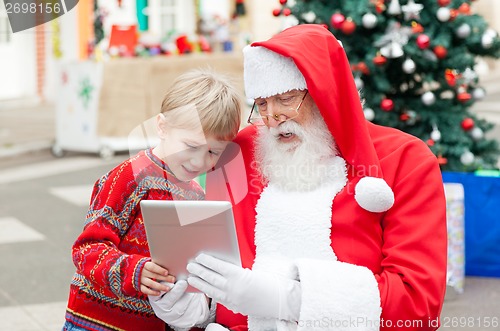 Image of Santa Claus And Boy Using Digital Tablet