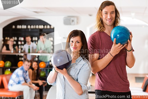 Image of Man And Woman Holding Bowling Balls in Club