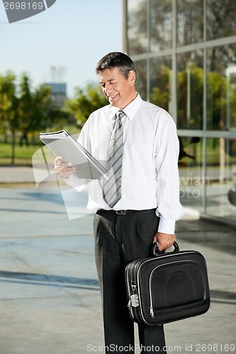 Image of Professor Reading Book While Standing On College