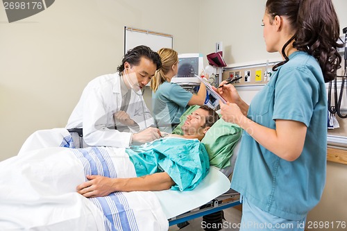 Image of Doctor And Nurses Examining Patient In Hospital