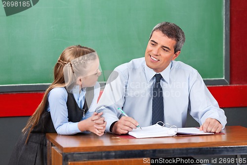 Image of Male Teacher Looking At Schoolgirl In Classroom