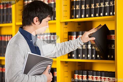 Image of Male Student Selecting Book In Library