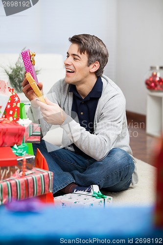 Image of Smiling Man Holding Christmas Presents At Home