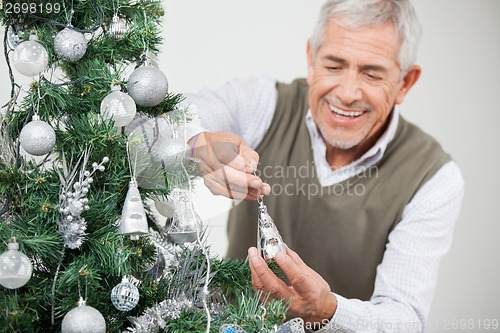 Image of Man Smiling While Decorating Christmas Tree