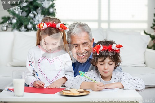 Image of Grandfather Assisting Children In Writing Letters To Santa Claus