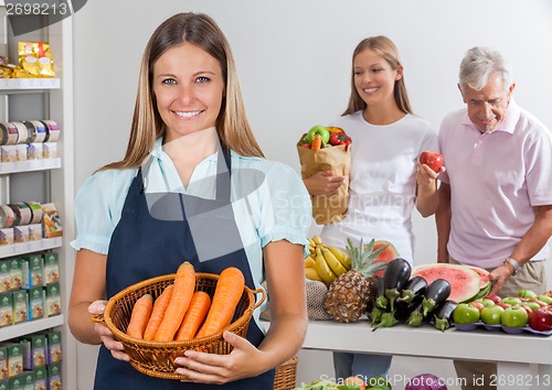 Image of Saleswoman Holding Carrot Basket At Supermarket