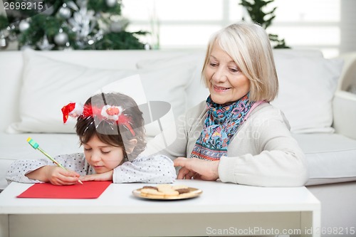 Image of Grandmother Looking At Boy Writing Letter To Santa Claus