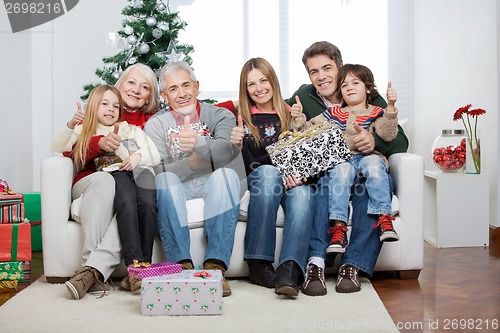 Image of Family With Christmas Presents Sitting On Sofa
