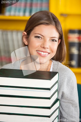 Image of Beautiful Student With Piled Books Smiling In Library