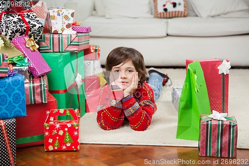 Image of Boy Lying Besides Stacked Christmas Gifts