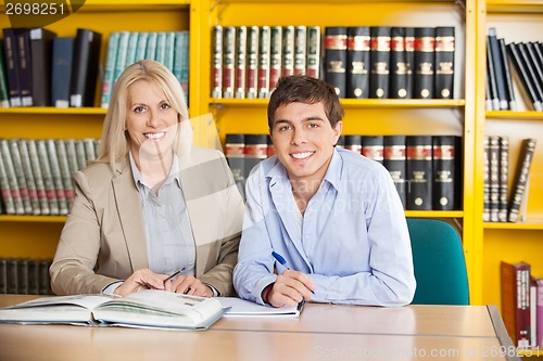 Image of Student And Teacher With Books Sitting At Table In Library