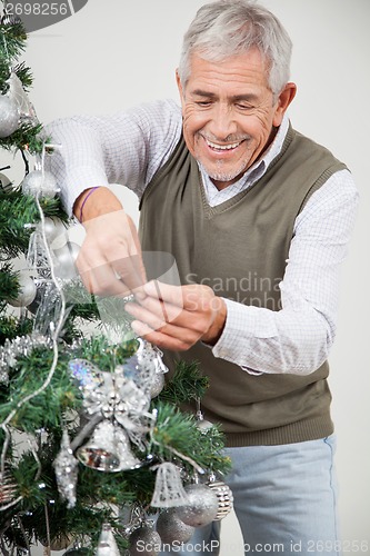Image of Man Decorating Christmas Tree With Silver Ornaments