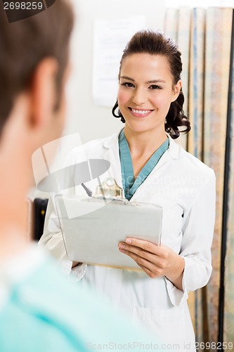 Image of Doctor With Clipboard Standing By Patient