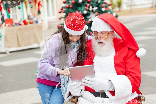 Image of Girl And Santa Claus Using Digital Tablet