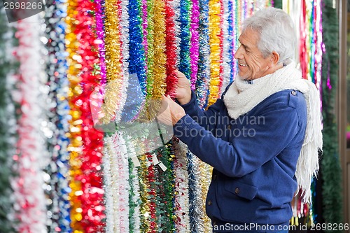 Image of Man Choosing Tinsels In Christmas Store