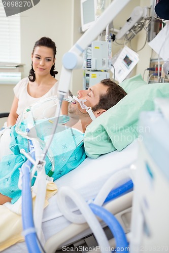 Image of Woman Looking At Male Patient Resting On Bed