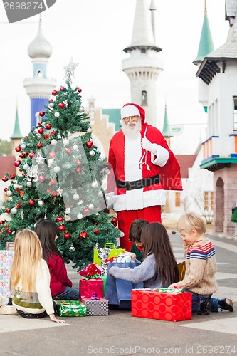 Image of Santa Claus With Children Opening Presents By Christmas Tree