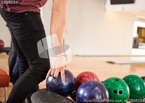 Image of Young Man Choosing Bowling Ball From Rack