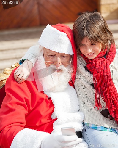 Image of Boy And Santa Claus Using Smartphone