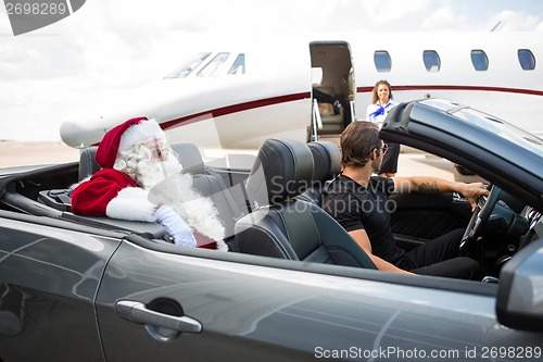 Image of Santa And Chauffeur In Convertible While Airhostess Against Priv