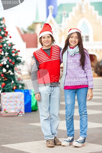 Image of Friends Wearing Santa Hat Standing In Courtyard