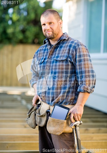 Image of Carpenter With Digital Tablet And Hammer In Tool Belt At Site