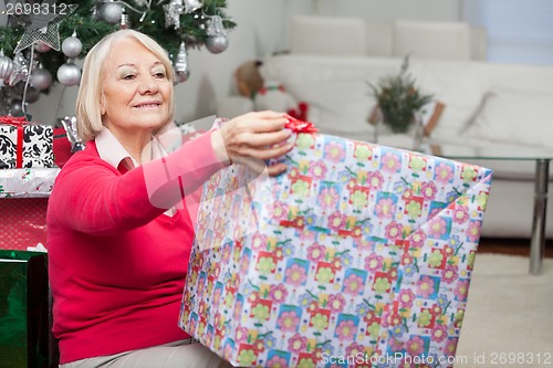 Image of Senior Woman Opening Christmas Present