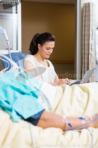 Image of Woman Using Laptop While Sitting By Patient
