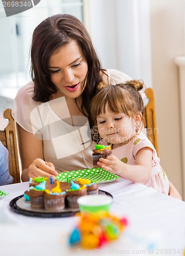 Image of Mother With Girl Eating Cupcake At Birthday Party