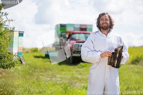 Image of Beekeeper In Holding Smoker At Apiary