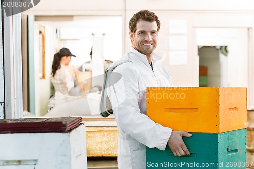 Image of Male Beekeeper Carrying Stack Of Honeycomb Crates